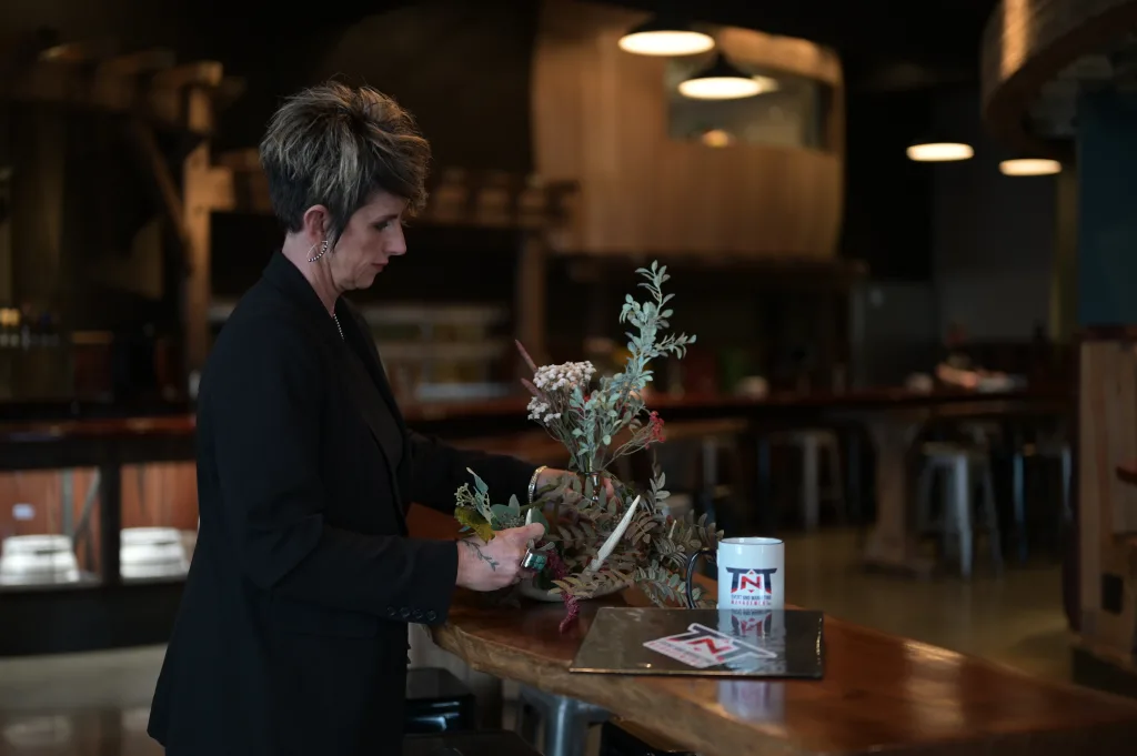 Tif Taylor-Robertson decorates a table with greenery and mug with t-n-t event and marketing management logo