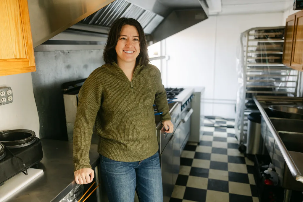 Jess Tolman-Stickney stands inside Fika Food truck. Black and White checker floors