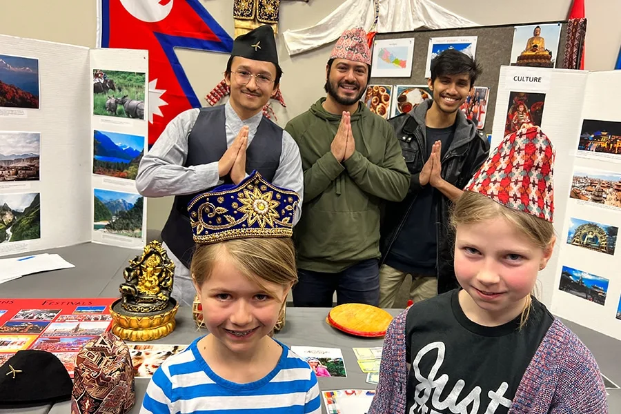 Children pose with traditional hats at cultural expo booth