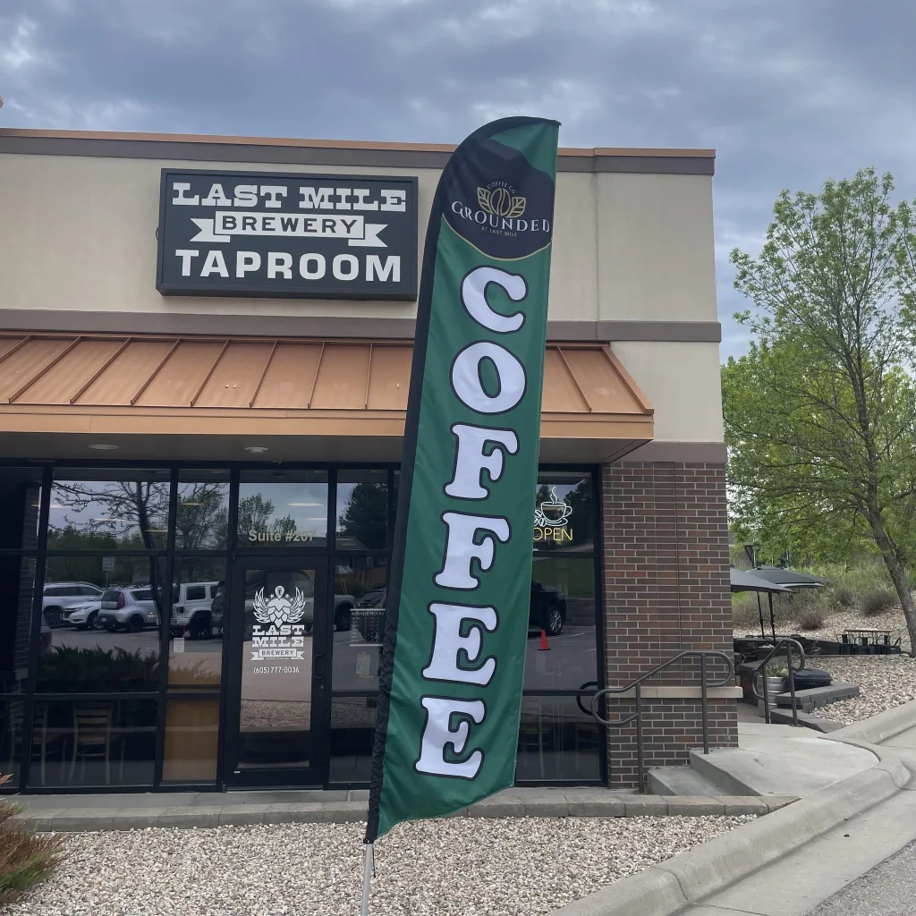 Exterior photo of last mile brewery with flag that says grounded coffee