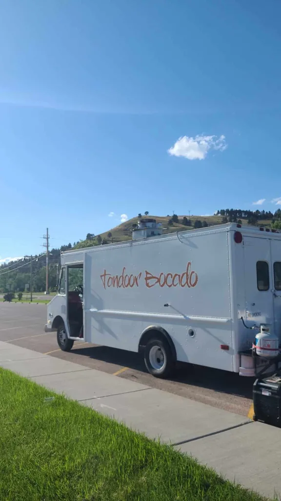 White food truck orange text reads tandoor bocado