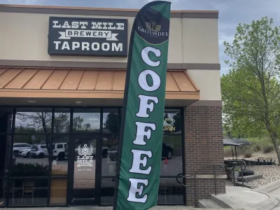 Exterior photo of last mile brewery with flag that says grounded coffee